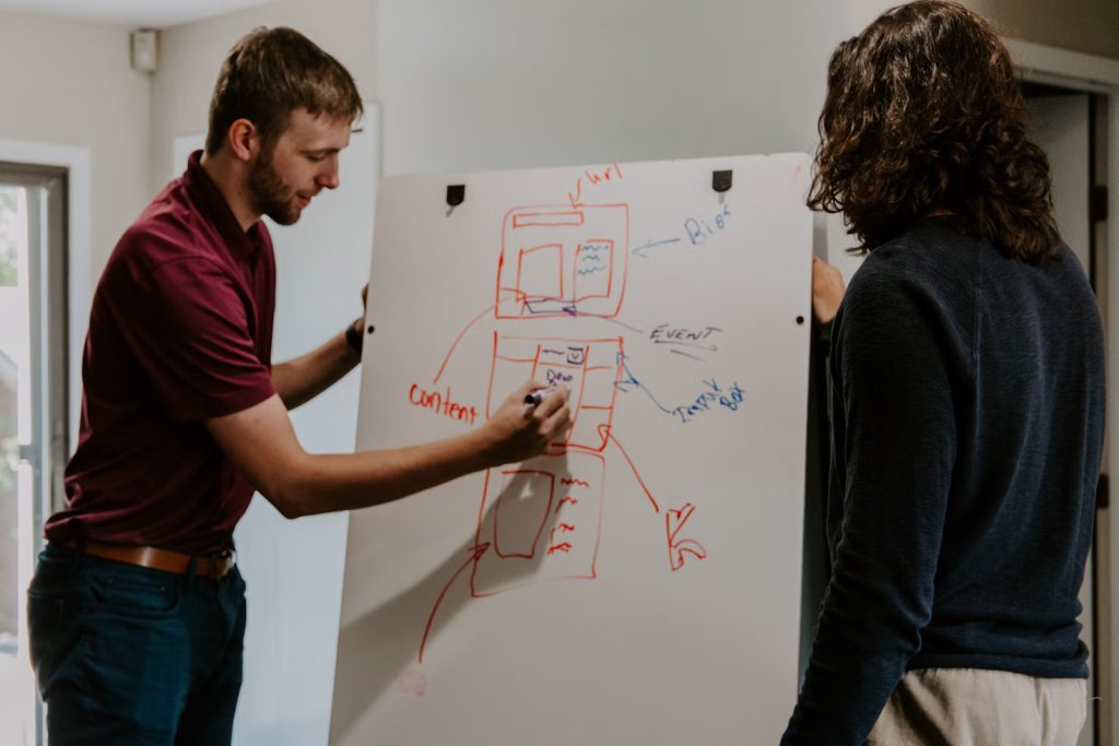 Two people brainstorming website structure and content flow on a whiteboard, illustrating early stages of a strong SEO strategy.