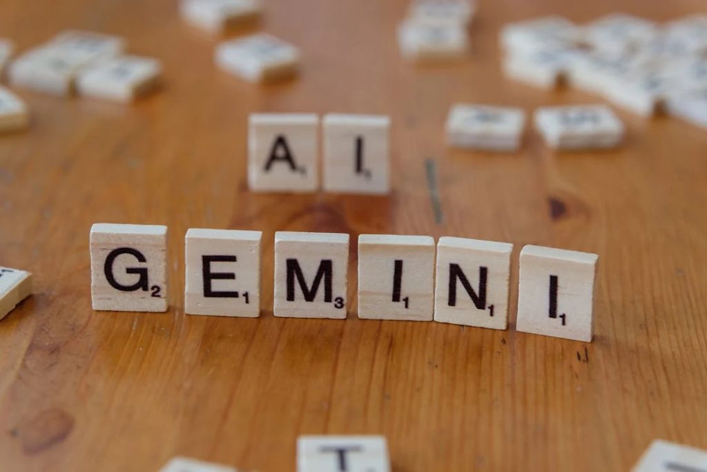 Scrabble tiles spelling out "GEMINI AI" on a wooden table.